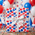 Red and blue polka dot birthday wrapping paper by Wrapped Studios, tied with a white bow in a festive party scene.