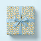 Popcorn birthday wrapping paper with a light blue satin ribbon on a gift box, by Wrapped Studios.