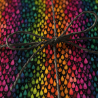 Close-up of a gift wrapped in colorful abstract teardrop patterned wrapping paper with a simple twine bow.