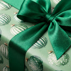 Luxury green Christmas wrapping paper with ornament pattern and emerald satin ribbon bow by Wrapped Studios.