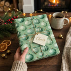 Green Christmas ornament wrapping paper with gold twine on a holiday gift by Wrapped Studios.