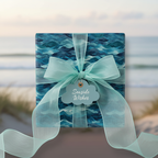 Elegant ocean wave wrapping paper with sheer teal ribbon and "Seaside Wishes" tag.