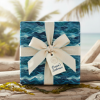 Ocean wave wrapping paper on a gift box with a tan ribbon and "Ocean's Embrace" tag, perfect for beach themed gifts.