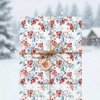Christmas wrapping paper with red berries and blue leaves, tied with rustic twine and a round gift tag, against a snowy winter background.