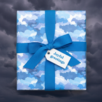 Square gift wrapped in blue patterned paper with a matching bow and "Joyful Greetings" tag.