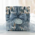 Square gift box wrapped in winter forest print wrapping paper with a blue sheer ribbon and bow.