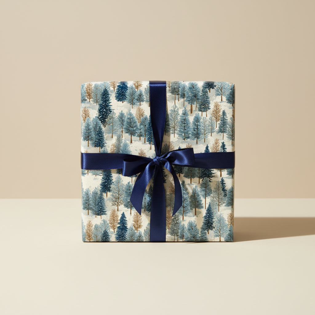 Square gift box wrapped in modern blue tree print Christmas wrapping paper with a navy satin ribbon.