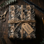 Rustic Christmas gift wrap with pinecone and fir branch design, tied with twine and "Happy Holidays" tag.