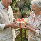 Senior couple exchanging a gift wrapped in luxury floral wrapping paper with coral bow by Wrapped Studios.