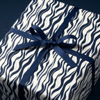Modern gift wrap: Navy blue wavy line pattern on cream paper with a navy ribbon bow.