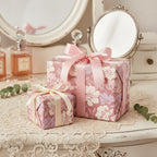 Elegant floral wrapping paper in shades of mauve and pink, tied with satin ribbon.