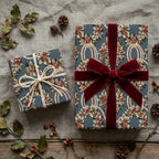 Luxury Christmas wrapping paper with blue holiday wreath pattern and velvet ribbon by Wrapped Studios.