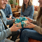 Western cowboy boot wrapping paper with a teal bow on a gift being exchanged. By Wrapped Studios.