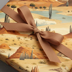 Gift wrapped in tan desert landscape wrapping paper with a brown ribbon.