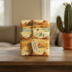 Gift box wrapped in desert landscape wrapping paper with twine, tag, and a cactus in the background.
