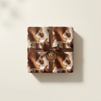 Cow print wrapping paper with brown ribbon and "Wrapped Studios" gift tag.