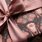 Boho skull wrapping paper with roses and a dusty rose satin bow, rustic gift wrap by Wrapped Studios.