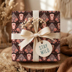 Boho western wrapping paper with steer skulls and roses by Wrapped Studios, tied with a cream fabric bow.