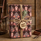 Rustic western wrapping paper with boho cow skulls, roses, and twine bow by Wrapped Studios.