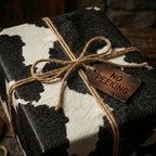 Black and white cow print wrapping paper with rustic twine ribbon and "No Peeking" tag.
