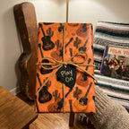 Orange acoustic guitar wrapping paper with a rustic music theme by Wrapped Studios.
