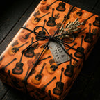 Rustic acoustic guitar wrapping paper on a gift box with black twine, by Wrapped Studios.