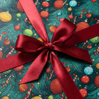 Christmas gift wrap with red satin bow. Ornament and candy cane pattern on teal paper.