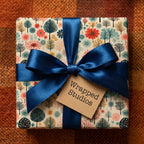 Wrapped Studios floral wrapping paper on gift box with blue ribbon and tag.