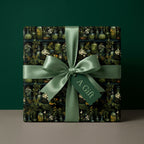 Square gift wrapped in botanical herb and jar wrapping paper with a matching satin ribbon and gift tag.