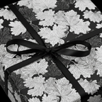 Elegant gift wrapped in black and white floral wrapping paper with a classic black ribbon bow.