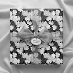 Elegant black and white floral wrapping paper with sheer ribbon, ideal for upscale gifts.
