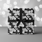 Elegant gift box wrapped in black and white floral wrapping paper with a satin ribbon bow.