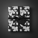 Elegant gift box in black floral wrapping paper with a matching ribbon and "Timeless Elegance" tag.
