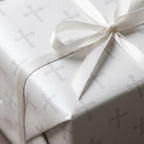 Elegant baptism wrapping paper with a silver cross pattern and white satin bow by Wrapped Studios.
