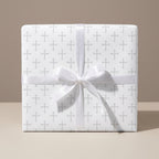 Elegant baptism wrapping paper with a grey cross pattern and white satin bow by Wrapped Studios.