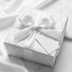 Elegant white damask wedding wrapping paper with satin bow on a luxury gift box by Wrapped Studios.