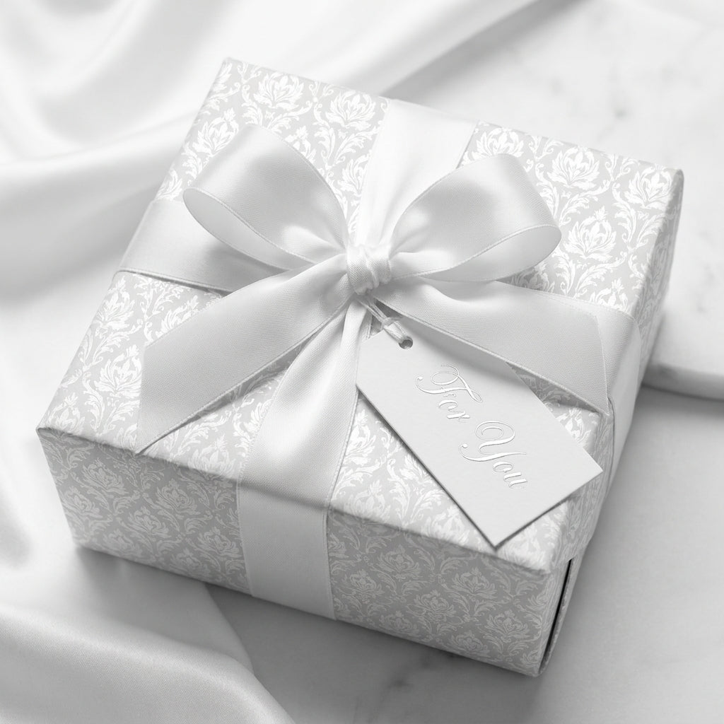Elegant white damask wedding wrapping paper with satin bow on a luxury gift box by Wrapped Studios.