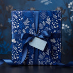 Elegant dark blue floral wrapping paper on a gift box with satin ribbon and "Special Delivery" tag.