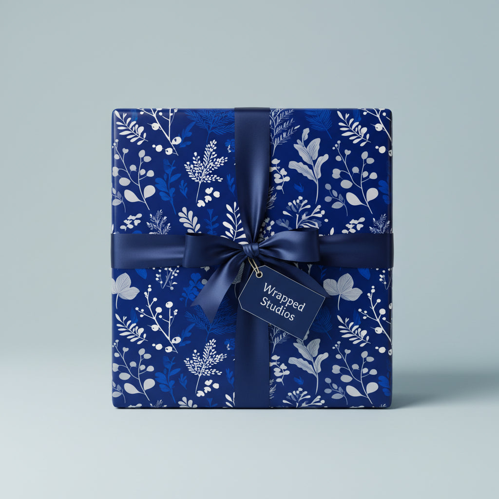 Elegant gift wrapped in navy blue floral wrapping paper with satin ribbon and a "Wrapped Studios" tag.