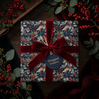 Luxury botanical Christmas wrapping paper with a red velvet bow and gift tag, by Wrapped Studios.