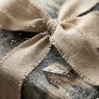 Rustic Christmas gift wrap with frayed linen bow and snowy cabin design, Wrapped Studios.