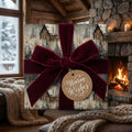Rustic Christmas gift wrap with cabin scene, burgundy velvet bow, and “Warm Wishes” tag. Wrapped Studios.