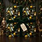 Square Christmas gift wrapped in a green and gold ornament pattern with a velvet bow.
