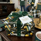 Wrapped Studios gift with dark green and gold Christmas ornament wrapping paper, velvet bow.