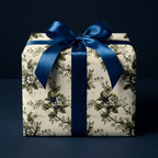 Elegant square gift box with floral wrapping paper and a navy blue satin bow.