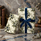 Two floral-patterned gift boxes with blue ribbons on a marble surface. Woodland blooms floral wrapping paper.
