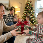 Boy receives gift in pinecone Christmas wrapping paper with red satin bow. Wrapped Studios holiday gift wrap.