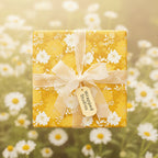 Square gift wrapped in mustard floral wrapping paper with a cream bow, daisy background.