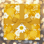 Golden floral wrapping paper on a square gift box tied with a matching ribbon and daisy tag.