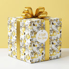 Luxury gold Christmas wrapping paper with ornament pattern and gold bow on a gift box by Wrapped Studios.